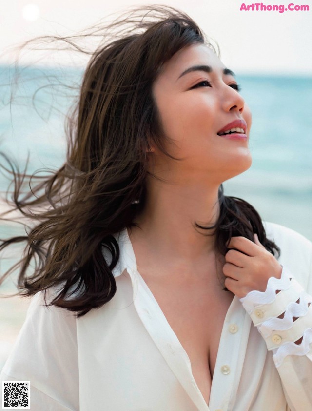 A woman with long brown hair standing on a beach.