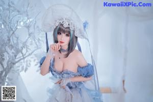 A woman in a blue and white dress holding a fan.