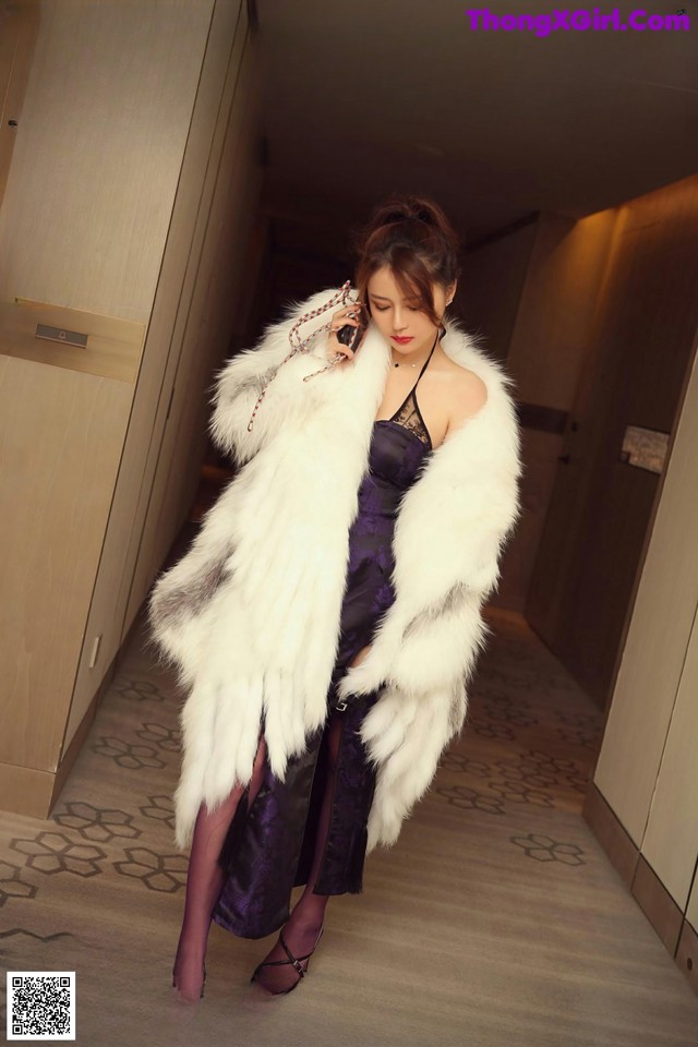 A woman in a fur coat talking on a cell phone.