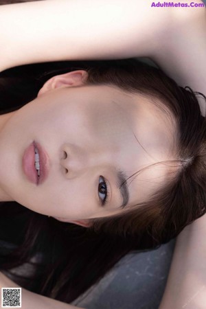 A woman laying on a table with her hand on her head.