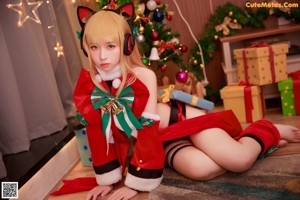 A woman sitting on a bed next to a christmas tree.