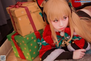 A woman sitting on the floor in front of a Christmas tree.