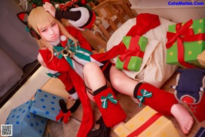 A woman sitting on the floor in front of a Christmas tree.