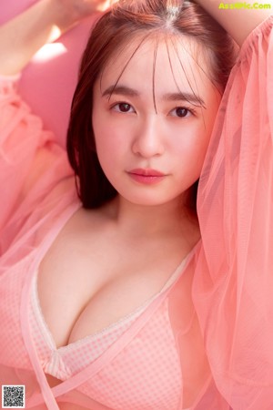 A woman in a pink lingerie sitting on a pink surface.