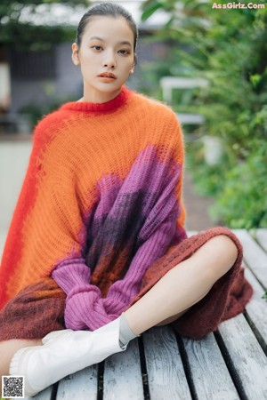 A young girl in an orange sweater looking up at the sky.