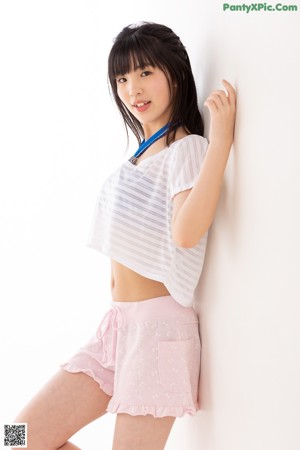 A young woman in a white shirt and pink shorts.