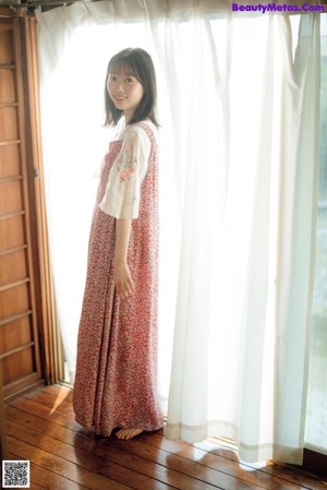 A woman in a red and white dress smiles at the camera.