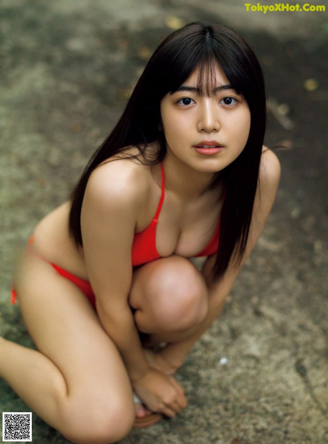 A woman in a red bikini crouching on the ground.