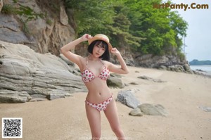 A woman in a bikini and a straw hat posing for a picture.