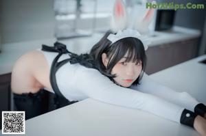 A woman in a bunny costume sitting on a blue chair.