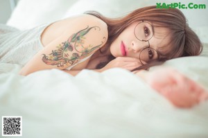 A woman with a tattoo on her arm holding a pair of glasses.