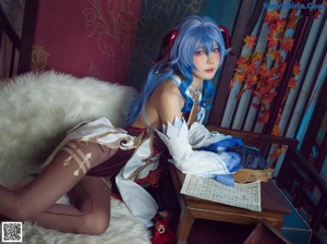 A woman with blue hair is sitting on a white fur rug.