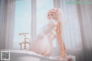 A woman in a white lingerie posing in front of a window.