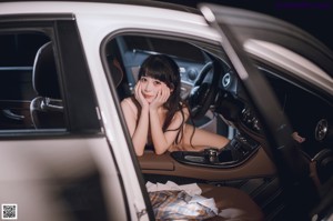 A woman sitting in the back of a white car.