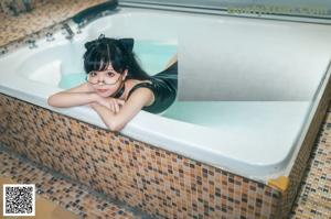 A woman in a black bathing suit is sitting in a pool.