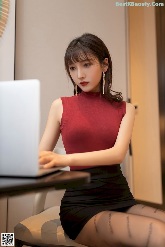 A woman sitting at a desk with a laptop computer.