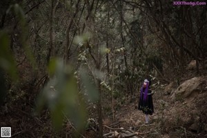 A woman with purple hair holding a sword in the woods.