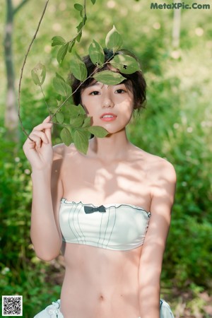 A woman in a green bikini standing in the grass.