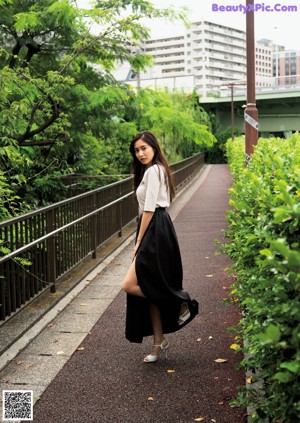 A woman in a white dress sitting on a bench.