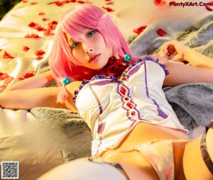 A woman with pink hair sitting on a bed holding a red ball.
