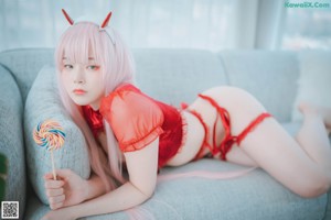 A woman in a red lingerie sitting on a blue couch.