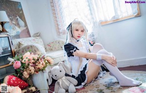 A woman sitting on a rug holding a teddy bear.