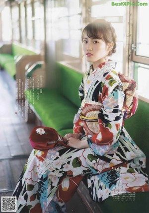 A woman in a kimono leaning against a wall.