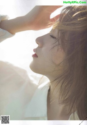 A woman in a white shirt sitting on a beach.