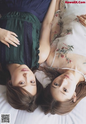 A couple of women sitting on top of a grass covered field.