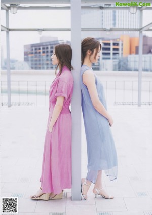 A couple of women sitting on top of a grass covered field.
