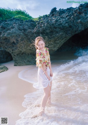 A woman in a bathing suit is standing on a beach.