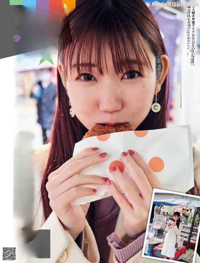 A woman eating a piece of food in front of a magazine.