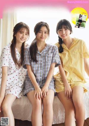 A couple of young women laying on top of a bed.