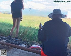 A naked woman sitting on a train track next to a man.