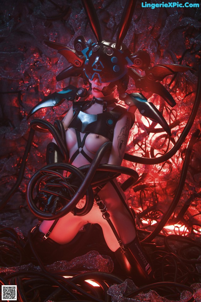 A woman in a black and red outfit is sitting on a pile of wires.