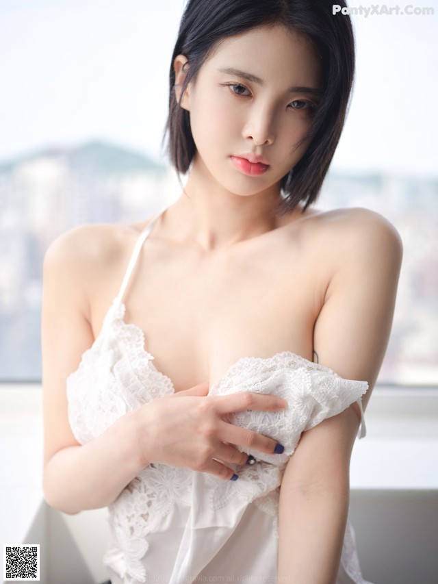 A woman in a white lingerie posing for the camera.