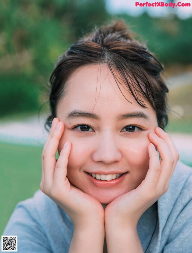 A woman with her hands on her face smiling.