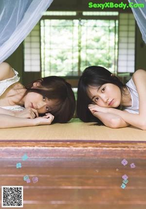 Two young women sitting next to each other on a bench.