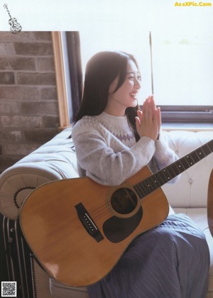 A woman standing by a window looking out the window.