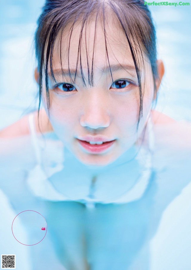 A young woman in a swimming pool with her hands on her head.