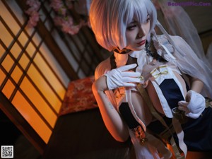 A woman in a white and blue outfit sitting on a bed.