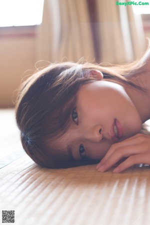 A woman laying on the floor in front of a window.
